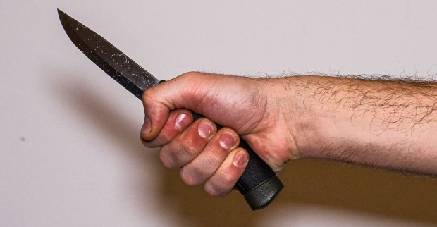Die Hand eines Mannes, der ein Messer hält.