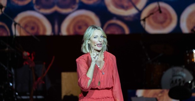 Monika Gruber in einem roten Kleid auf der Bühne.