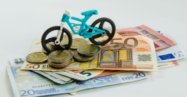 Ein Spielzeugfahrrad steht auf einem Stapel Geldscheine