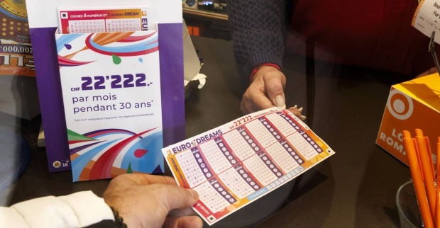 Jemand gibt einen ausgefüllten EuroDreams-Tippschein ab.