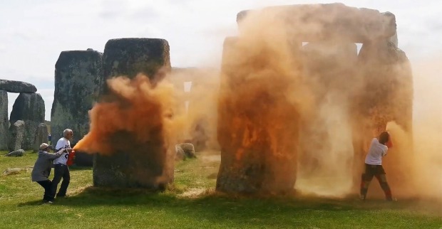 Zwei Klimaaktivisten besprühen Stonehenge mit oranger Farbe.