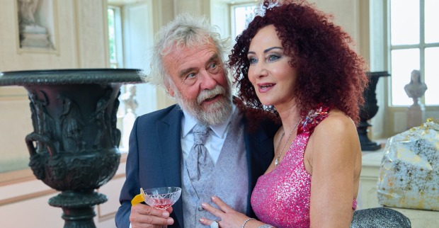 Mausi Lugner und Ernst Prost. Sie trägt ein pinkes Glitzerkleid und er einen blauen Anzug.