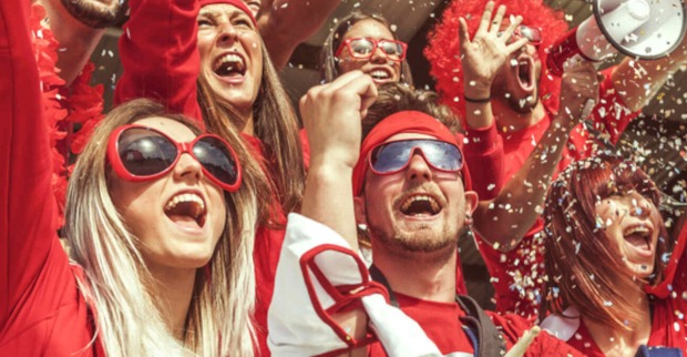 Mehrere Fußballfans sind in Rot gekleidet und jubeln