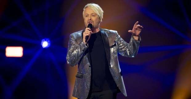 Anthony Ross in einem silber glitzernden Sakko auf der Bühne.