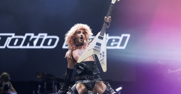 Bill von Tokio Hotel mit einem engen Lederoutfit und einer Gitarre auf der Bühne.
