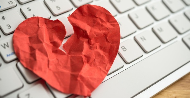 Gebrochenes Papier-Herz auf einer Computertastatur