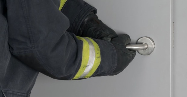 Feuerwehrmann bricht eine Wohnungstüre auf.