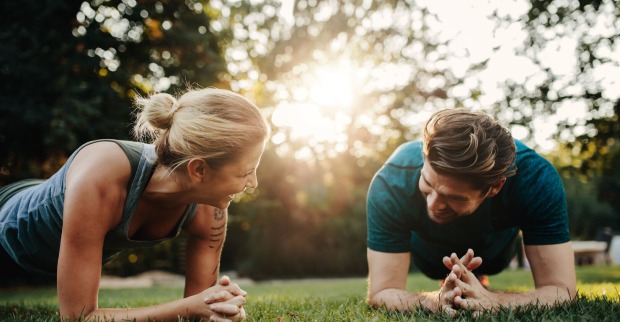 Eine Frau und ein Mann beim Sport im Park, sie führen eine Plank-Übung aus