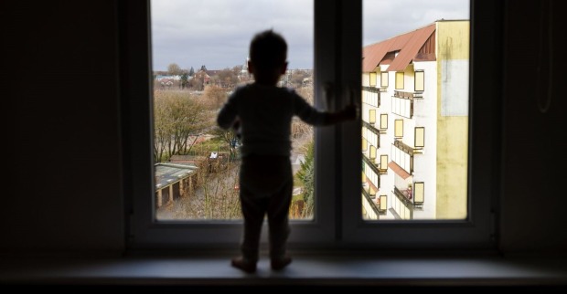 Ein Junge steht an einem Fenster.