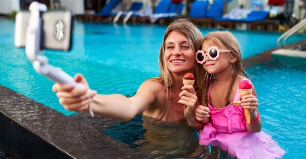 Mutter und Tochter mit Selfie-Stick am Pool