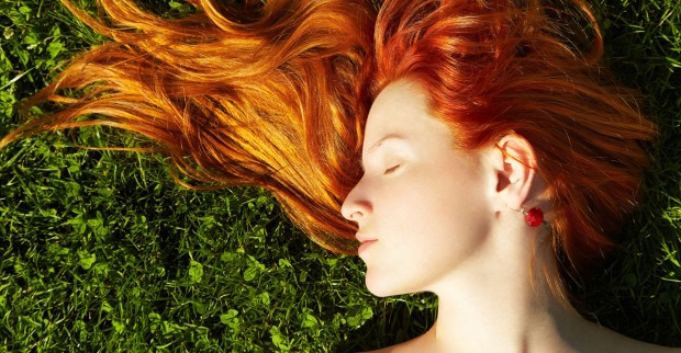 Frau mit roten Haaren liegt im Gras | Credit: iStock.com/Bakharev