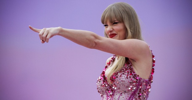 Talyor Swift, Blond in glitzerndem Oberteil auf der Bühne, sie zeigt in die Menge
