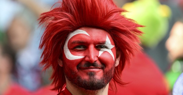 Fußballfan mit roter Perücke und den türkischen Landesfarben im Gesicht