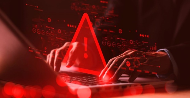 Mann sitzt vor Laptop rotes Warnsymbol leuchtet auf