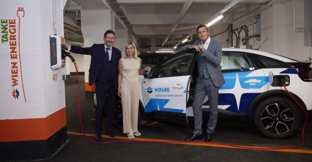 Drei Personen vor einem Auto, bei einer E-Ladestation