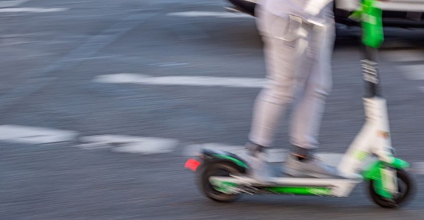 Jemand fährt mit einem E-Scooter über die Straße.