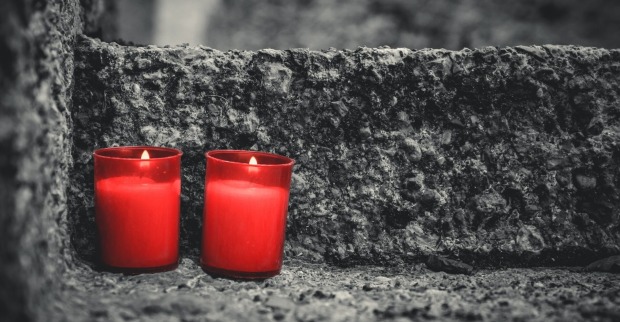zwei rote Kerzen am Grabstein