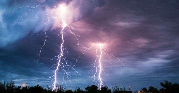 Gewitter mit Blitzen über Bäumen und Häusern.