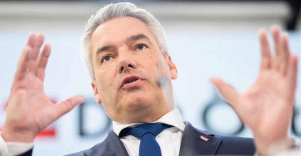 Bundeskanzler Karl Nehammer steht auf einer Bühne mit ausgestreckten Händen