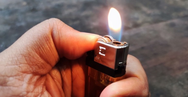 Ein Mann hält ein brennendes Feuerzeug in der Hand.