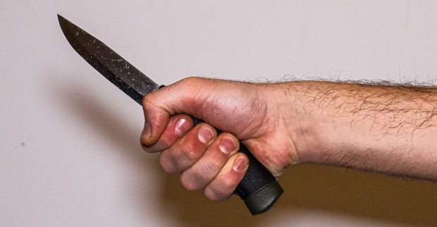 der Arm eines Mannes mit einem Küchenmesser in der Hand