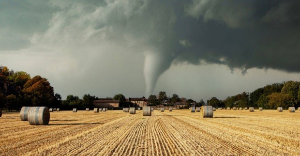 Ein Tornado fegt über ein Feld mit Heuballen.