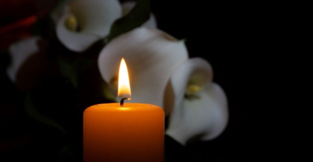 Bild einer Kerze mit weißen Blumen im Hintergrund – Symbolbild für die Trauer um den Tod von Autorin Sophie Kinsella