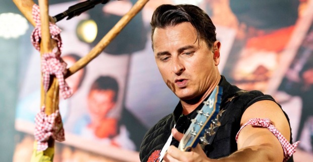 Andreas Gabalier spielt Gitarre auf einer Bühne.