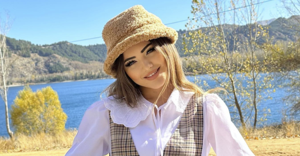 Influencerin Kübra Aykut mit einem Hut lächelt in die Kamera.