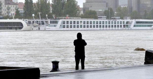 Ein Mann beobachtet die Donau mit gestrandeten Reiseschiffen.