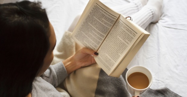 Frau sitzt mit Buch auf der Couch | Credit: iStock.com/Mima88