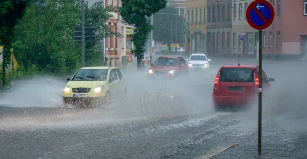Starker Regen auf den Straßen, Autos fahren durch zentimeterhohes Wasser