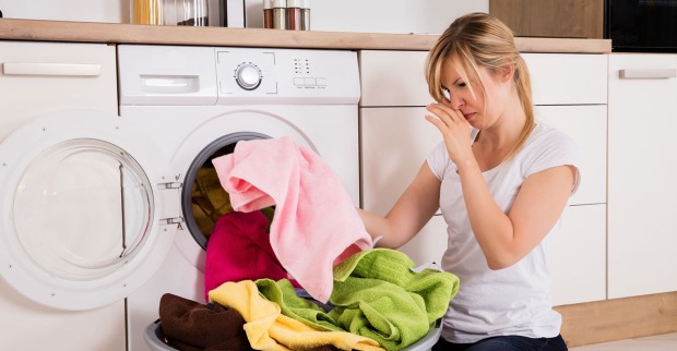 Frau sortiert die Wäsche vor der Waschmaschine | Credit: iStock.com/AndreyPopov