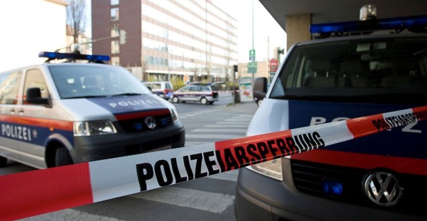Polizeiabsperrung und zwei Einsatzfahrzeuge vor einem Gebäude.