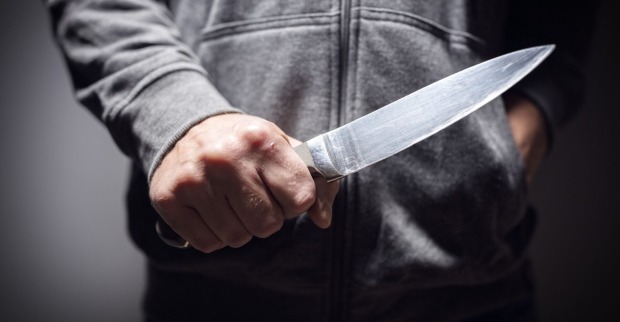 Ein junger Mann hält ein Messer in der Hand.