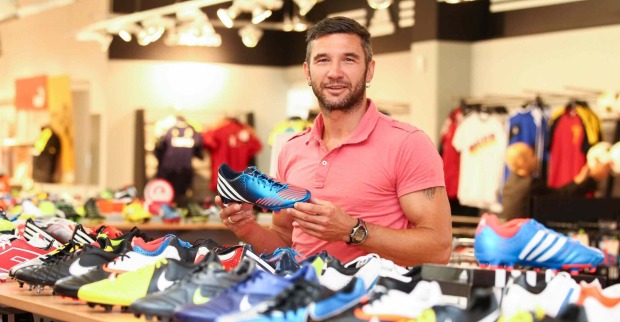 Thomas Winklhofer hält im Sportgeschäft einen Fußballschuh hoch.