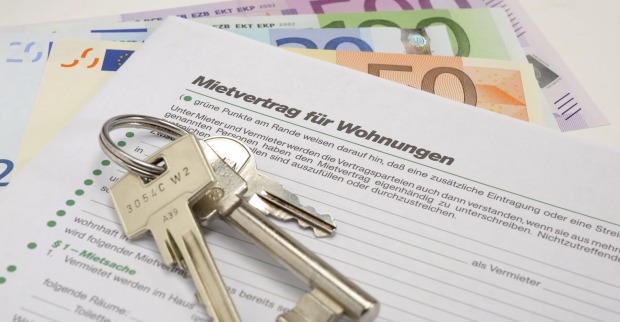 Geld, ein Schlüsselbund und ein Mietvertrag auf einem Tisch.
