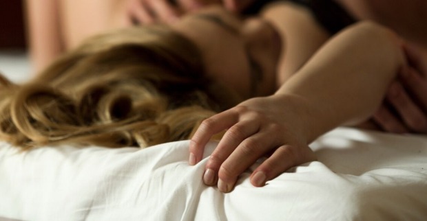 Eine Frau vergnügt sich im Bett mit jemanden.