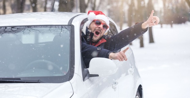 Ein Mann mit Weihnachtsmütze winkt aus dem Auto.