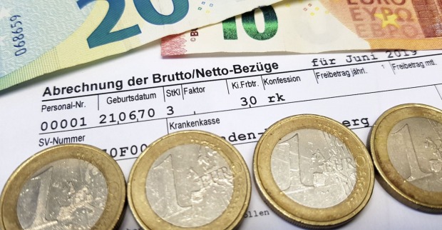 Lohnabrechnung und Euro-Münzen sowie -Scheine.