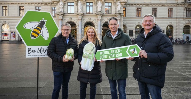 Mehrere Menschen mit Tafeln in der Hand stehen vor einem Rathaus
