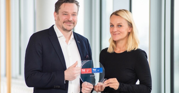 Ein Mitarbeiter und eine Mitarbeiterin von JTI Austria präsentieren eine Glastrophäe