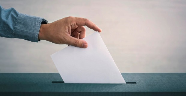 Mann wirft Stimmzettel in eine Box ein
