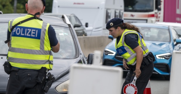 Zwei Polizisten kontrollieren ein Auto.