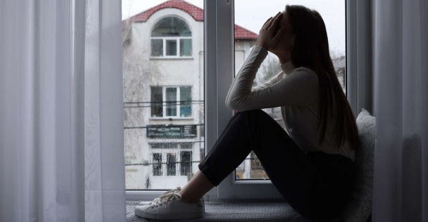 Eine verzweifelte Frau sitzt vor dem Fenster