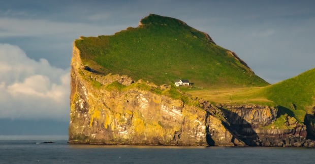 Haus auf einer Klippe einer wiesengrünen isländischen Insel
