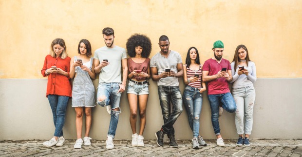 Mehrere Jugendliche starren auf ihr Handy