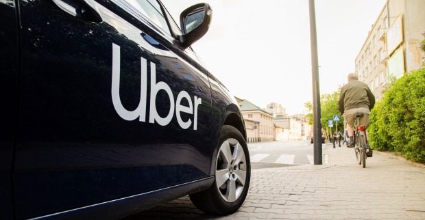 Ein Auto mit der Aufschrift "Uber" hält am Straßenrand.