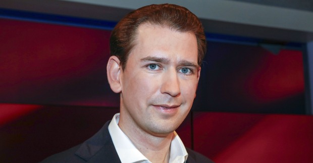 Porträtfoto von Sebastian Kurz in Anzug und weißem Hemd, vor dunklem, rötlich beleuchtetem Hintergrund – Blick in die Kamera, neutraler Gesichtsausdruck.