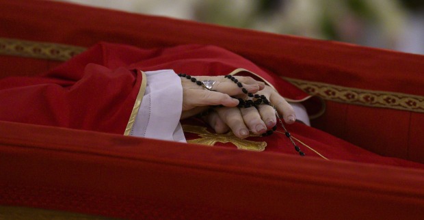 Papst Franziskus im offenen Sarg: Die gefalteten Hände halten einen schwarzen Rosenkranz, das purpurne Messgewand ist schlicht mit Goldborte verziert